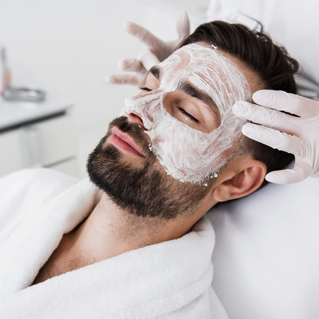 Professional applying facial to a relaxing man