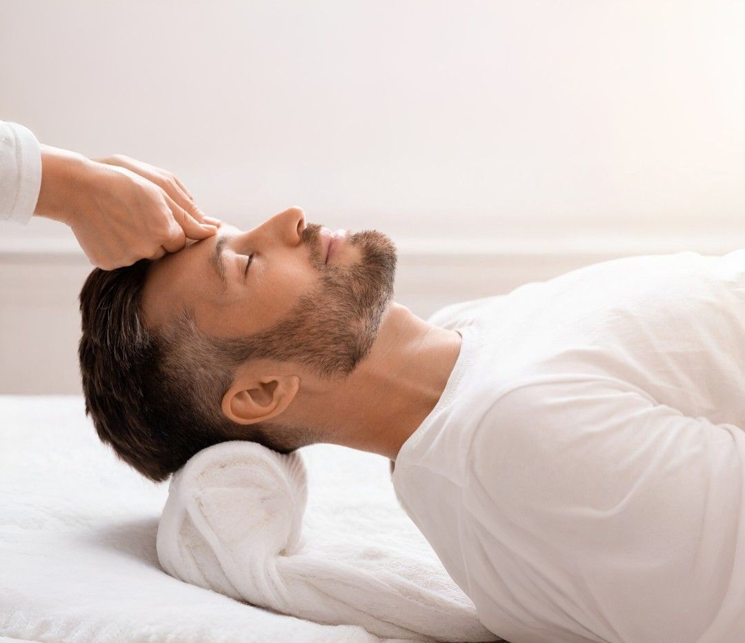 Man receiving a relaxing forehead and head massage treatment while lying on a spa bed
